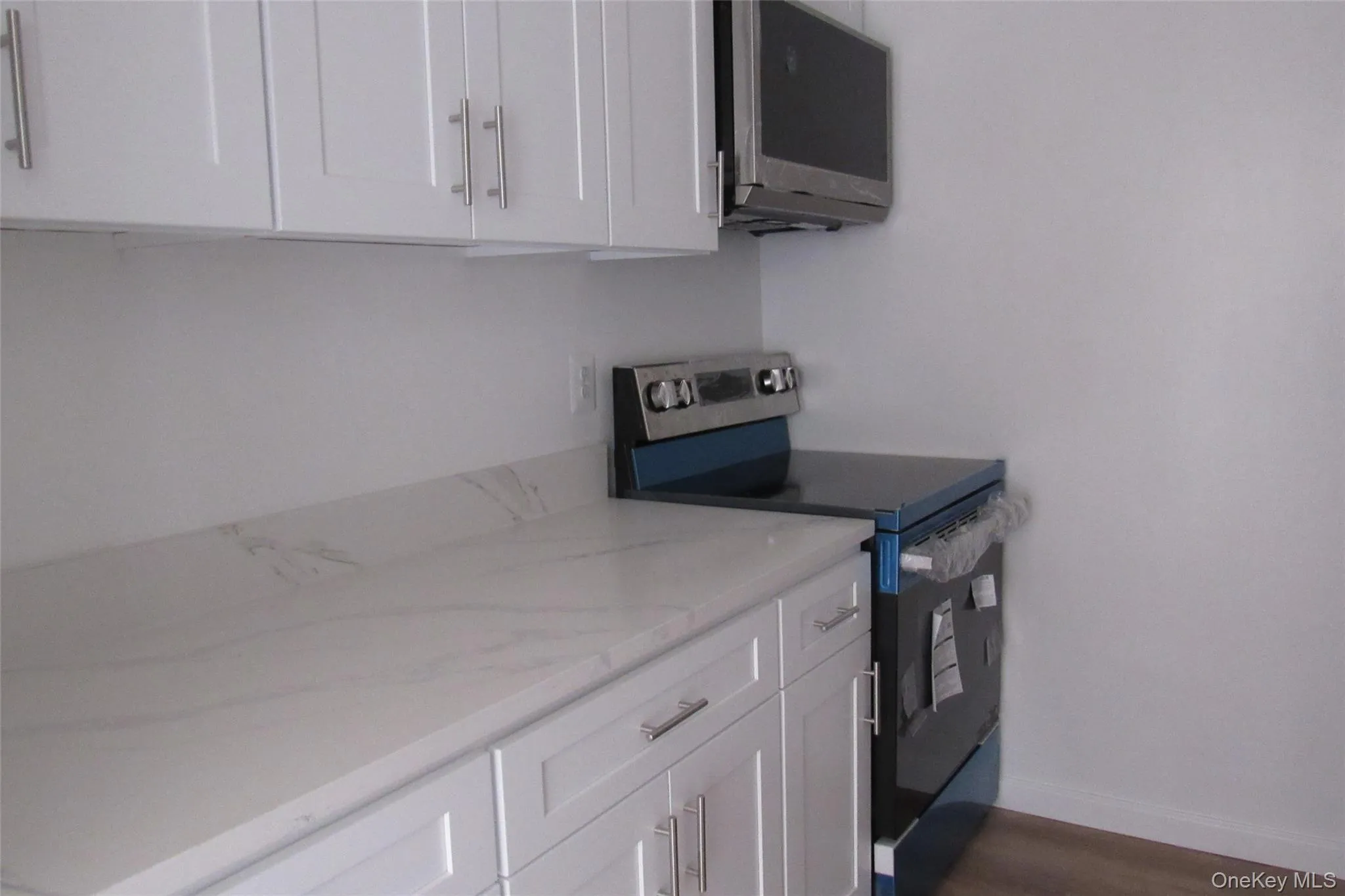 White shaker-style cabinetry, quartz countertops, stainless steel range, and over-the-range microwave White shaker-style cabinetry, quartz countertops, stainless steel range, and over-the-range microwave