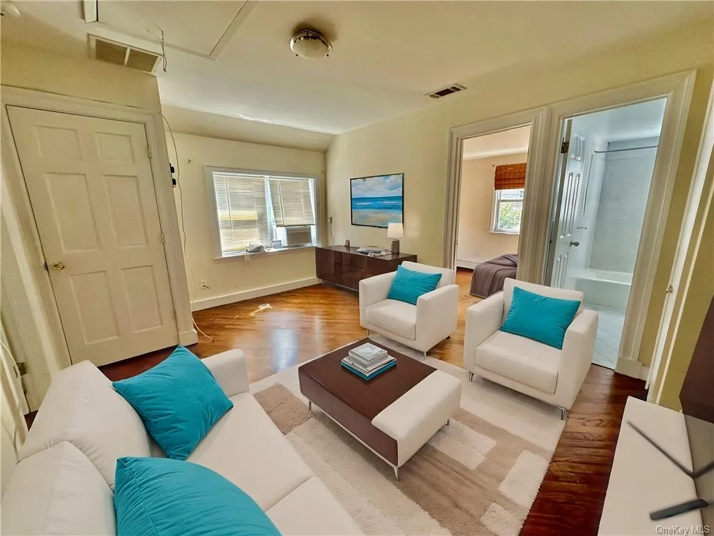 Virtually Staged - Upstairs center room staged as a sitting room with TV with access to the 2 bedrooms and a full bathroom with hardwood / wood-style floors Virtually Staged - Upstairs center room staged as a sitting room with TV with access to the 2 bedrooms and a full bathroom with hardwood / wood-style floors