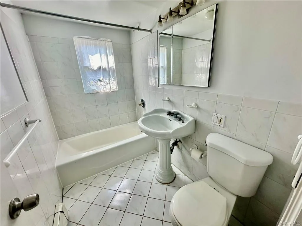 Upstairs full Bathroom featuring tiled shower / bath combo, tile walls, tile patterned flooring, and toilet Upstairs full Bathroom featuring tiled shower / bath combo, tile walls, tile patterned flooring, and toilet