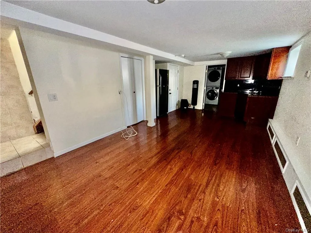 Lower Level - Unfurnished room optional for many uses, featuring an open concept kitchen, textured ceiling, dark wood-type flooring, and a full bathroom with stacked washer / drying machine Lower Level - Unfurnished room optional for many uses, featuring an open concept kitchen, textured ceiling, dark wood-type flooring, and a full bathroom with stacked washer / drying machine