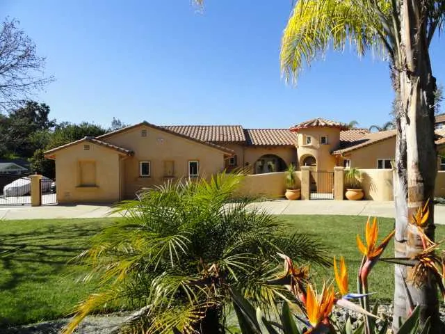 Front view of this Beautiful home from the street with circular driveway and gated entrance to 3 Car garage and backyard!