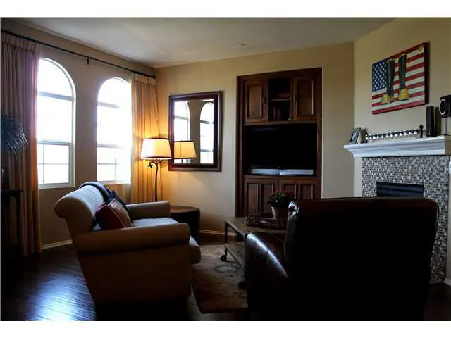 The living room has great natural light, built-in entertainment center, and fireplace with glass-tile surround