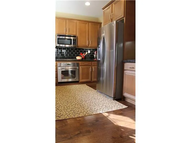 Stainless steel appliances and s/s cabinet pulls on tastesful wood cabinets w/ dark countertops add an elegant touch to the kitchen design