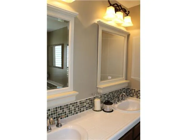 Dual sinks are complimented by the glass tile,classy mirrors & light fixtures