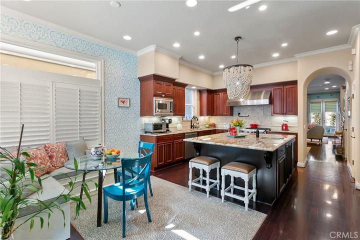This family/kitchen area has it all...giant island with extra seating, loads of rich wood cabinetry and stone counters and sunny informal dining space.