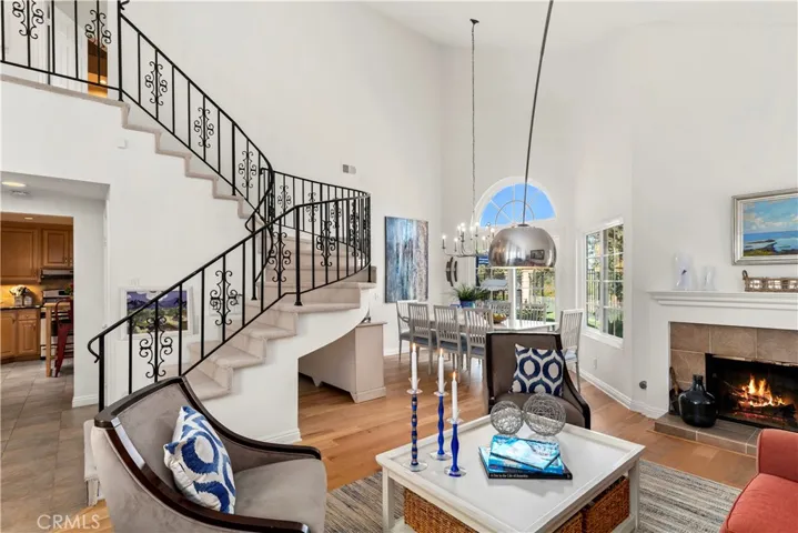Excellent view of the interior of the home with soaring ceilings, fireplace, wood floors, iron stsaircase, french sliding doors in the dining area. This home is absolutely stunning.