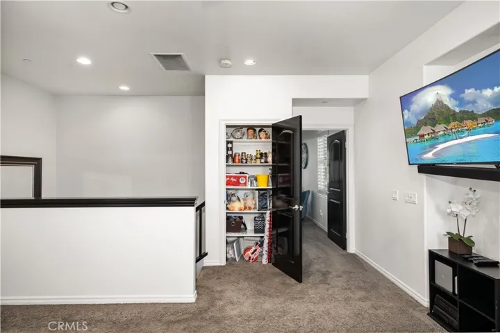 Up the stairs is a closet with built in shelving and dark wood door.
