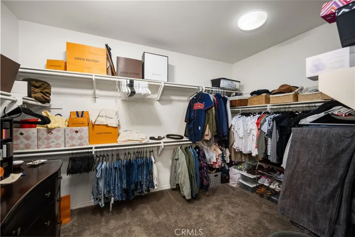 Primary walk-in closet has custom shelving, recessed lighting and is very spacious.