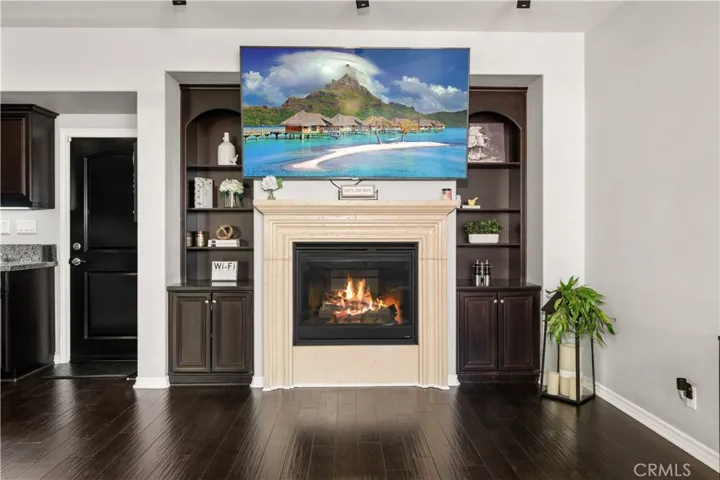 Entertainment center is built around the 80" tv! Wood shelves, and cupboards below. Above is a built in surround sound system. Ral wood flooring comlipents the entire room.