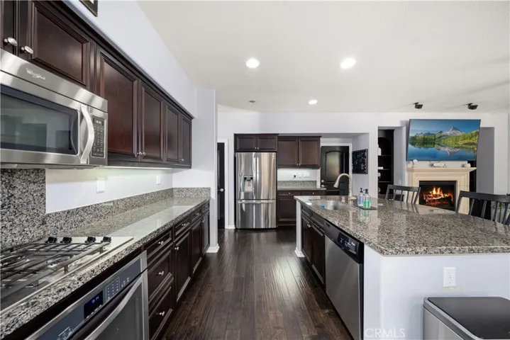 This photo allows you to see the microwave, cooktop, oven and your beautiful granite extra long contertop and center island . Stainless steel hardware trim all of the cupboards. ALL APPLIANCES ARE STAYING!! Recessed lighting above.