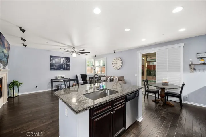 This photo allows you to see the fireplace in the left corner with 80" TV above. Granite island is every chefs dream with oversized stainless steel farm sink/faucet. Gorgeous granite, with dishwasher and cupboards below. Recessed lighting and tons of windows make this space light and bright!