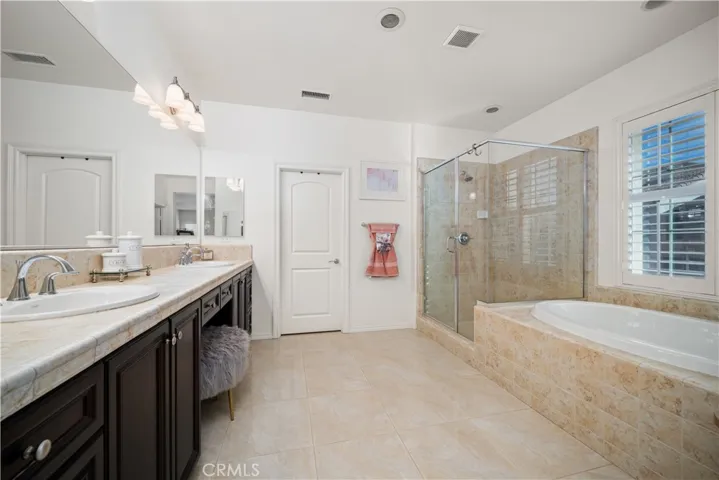 Primary en-suite is absolutlety spa like with your soaking tub, walk in shower, dual sink with vanity area in the middle, of course! Beige hues are soft and compliment the dark cupboards to nicely. Door in picture leads to your oversized walk-in closet! Stainless steel hardware and recessed lighting above.