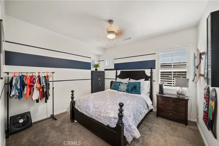 This 4th bedroom upstairs has walk-in closet, carpeted flooring and ceiling fan.