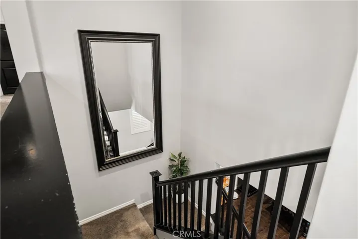 The hallway stairs has dark wood trim staircase and a dark trim mirror that is staying! Beige carpet is easy to clean.