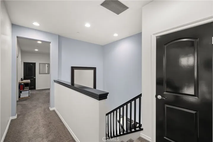 Upstairs loft greets you (behind photographer) next to this dark wood door closet. This floor plan is amazing, as the primary bedroom with en-suite and loft is on one side, and this hallway leads to the other 3 bedrooms and bathroom!