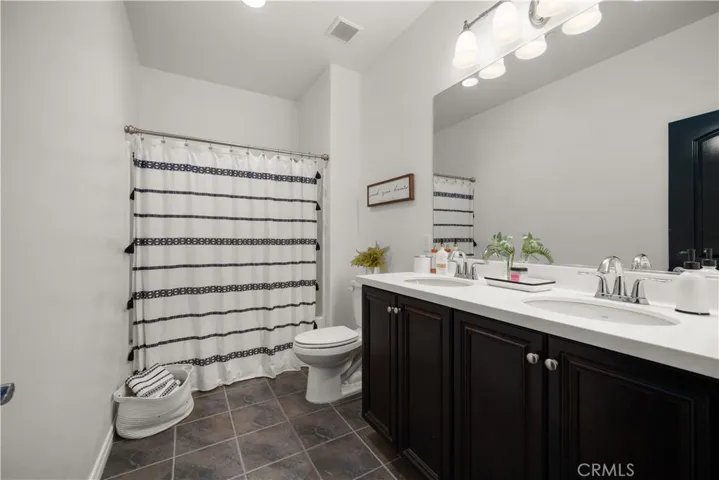 Upstairs bathroom is situated next to the 3 bedrooms (away from the primary bedroom). It features dual sinks, the same dark wood cupboards with stainless steel hardware, easy to clean ceramic tiled flooring, toilet and tub/shower. Recessed lighting as well as ligts above the sink.