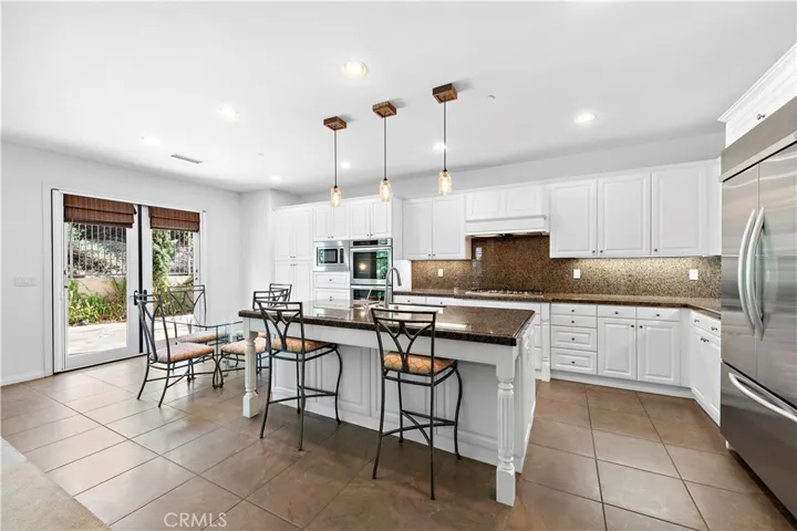 Oversized island in kitchen with sink, bar stool seating, osmosis water fountain, granite counter tops built in counter depth refrigerator and more!
