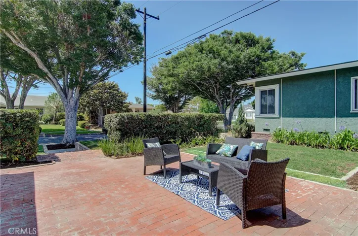 Sunny front brick patio sits behind privacy hedge...works great for additional entertaining space...