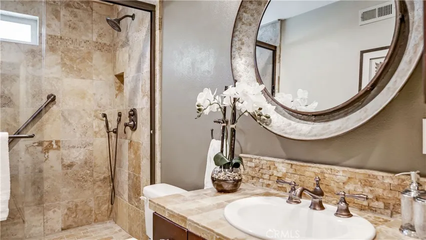 Downstairs bathroom has a dog washing station in the shower and beautiful travertine tile