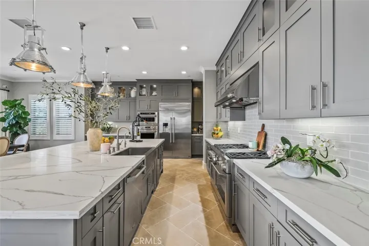 Kitchen with quartz countertops, large center island, floor to ceiling shaker cabinets, premium Monogram stainless-steel appliances including 48” commercial grade built-in refrigerator, 6-burner range with griddle and 2 ovens, built-in microwave, the 3rd oven, dishwasher and wine cooler.