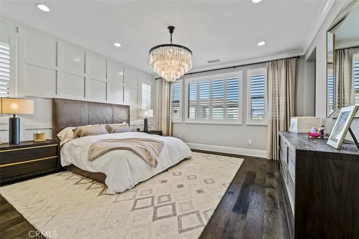 Master bedroom with grid accent wall, beautiful chandelier, custom window curtains