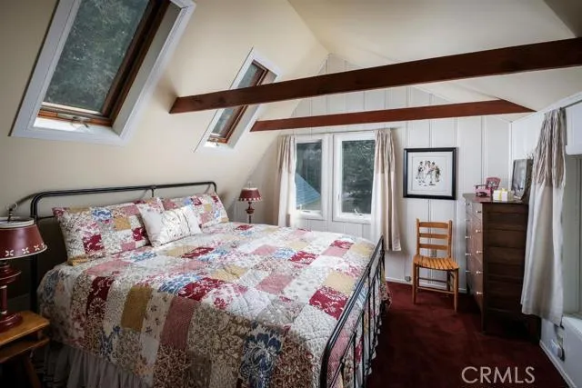 UPPER LEVEL BEDROOM WITH SKY LIGHTS AND VIEWS OF BACKYARD FOREST.