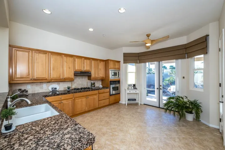 Kitchen with granite counters, stainless steel appliances, walk in pantry, desk area, and double door access to the patio.