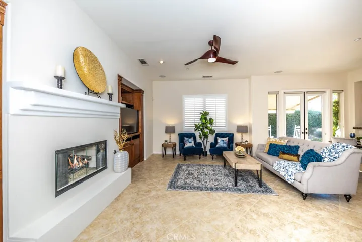 Family room with fireplace, mantel, and hearth, recessed lighting, built in cabinets, tile flooring, and ceiling fan.