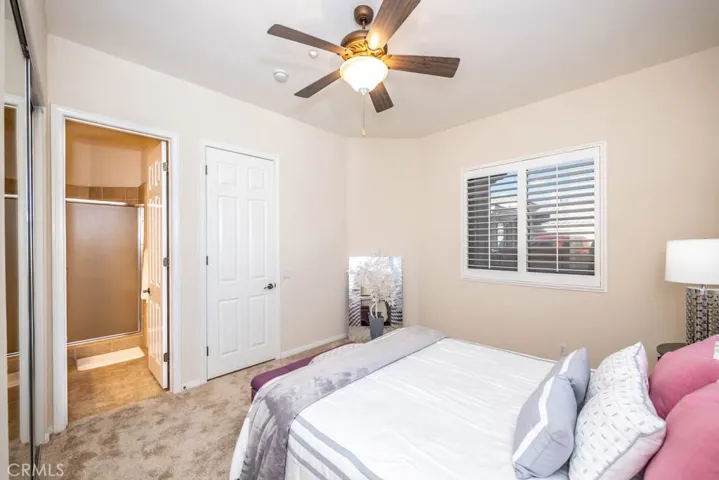 First bedroom with new carpet, ceiling fan, mirrored closet doors, and attached bath.