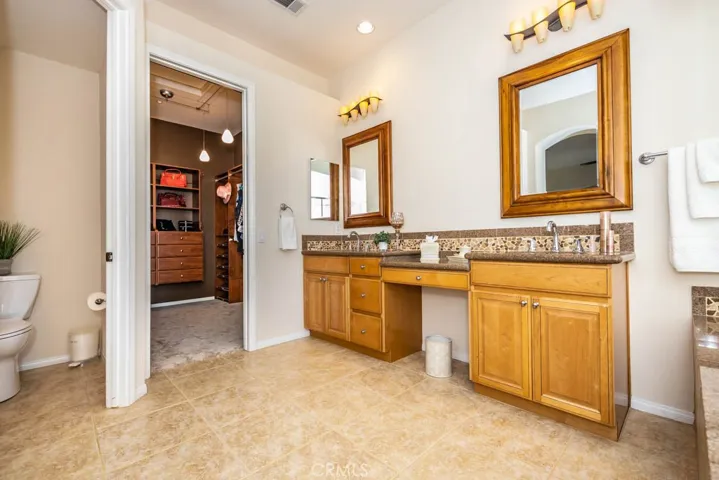 Master bathroom with dual sinks, toilet room, and large walk in closet with built ins.