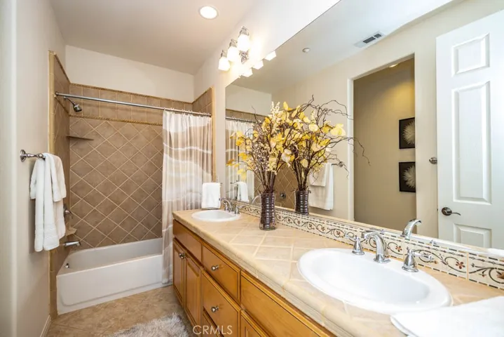 Hall full bath with dual sinks and tile counters and separate toilet room.