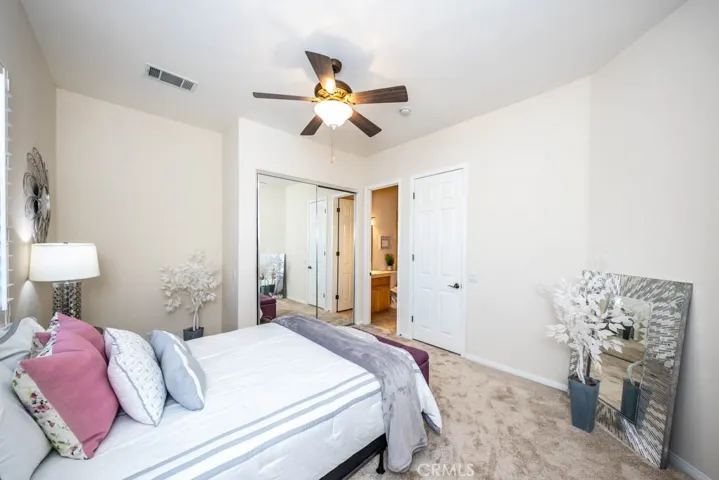 First bedroom with new carpet, mirrored closet doors, ceiling fan, and attached full bath.