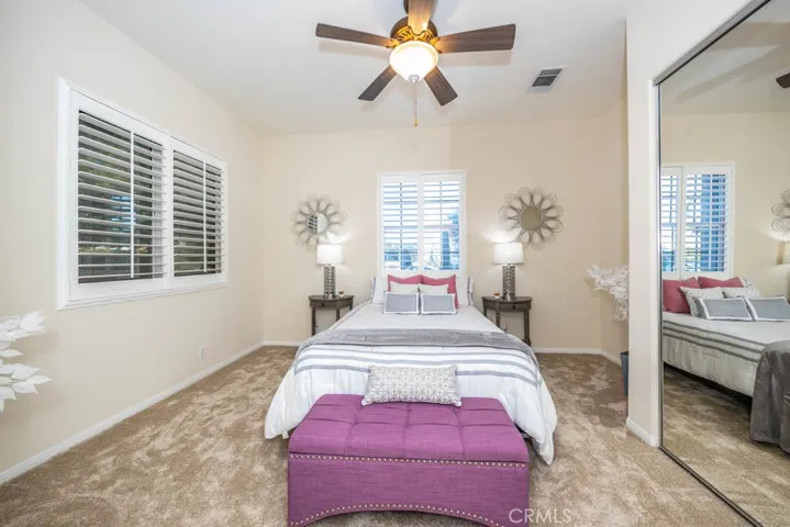  First bedroom with new carpet, mirrored closet doors, and ceiling fan.