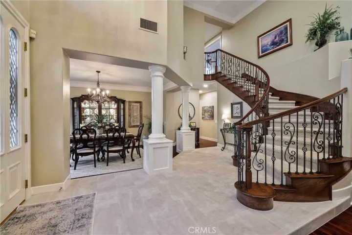 Formal entry with newer porcelain tile, elegant spiral wrought iron staircase.