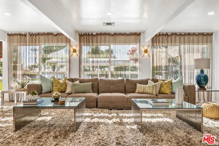 The great room, wall to wall windows looking onto to pool, grounds, and golf course beyond