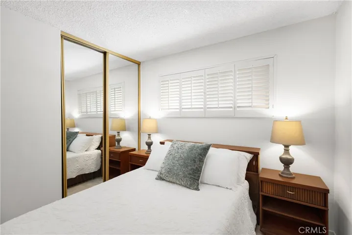 4th bedroom with wood shutters and mirrored closet doors
