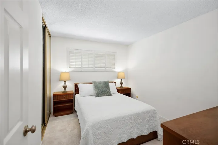 4th bedroom with wood shutters and mirrored closet doors