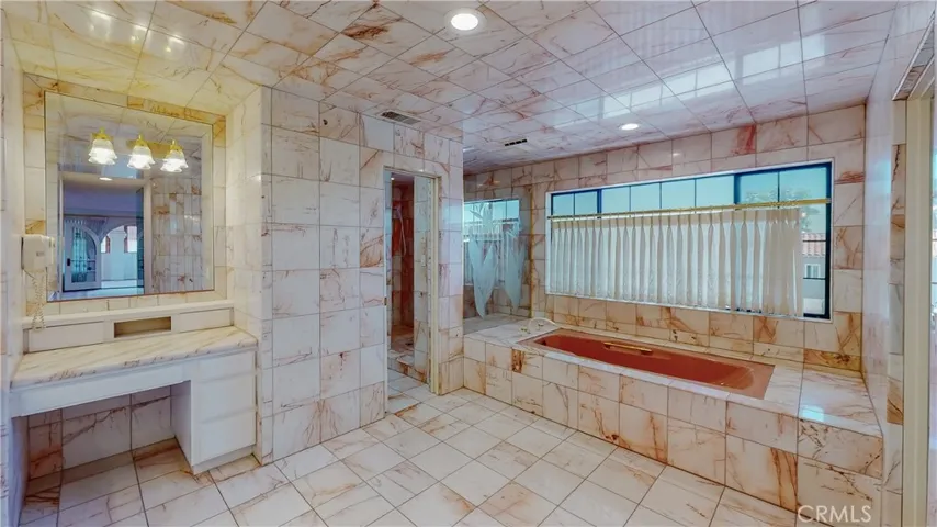 Luxurious marble surroundings in the primary bath, with dual basins, dual shower, make up station, soaking tub and privacy area