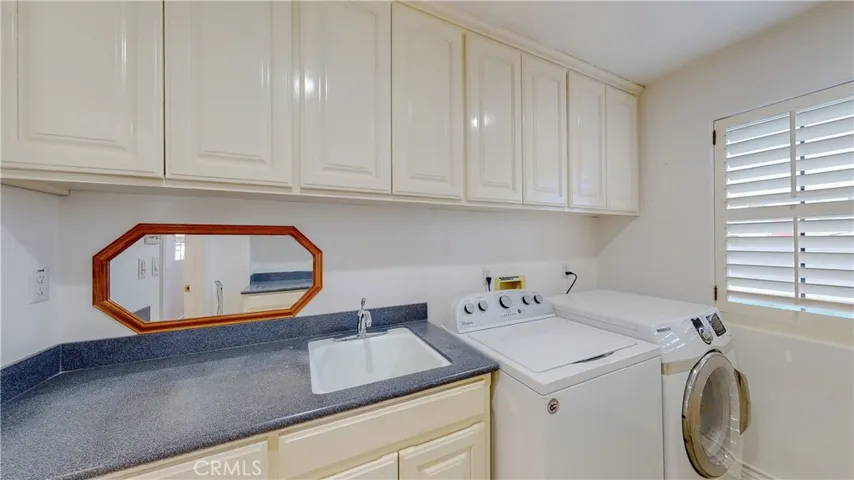 Convenient second level laundry room with a plethora of cabinetry, storage, and counter space