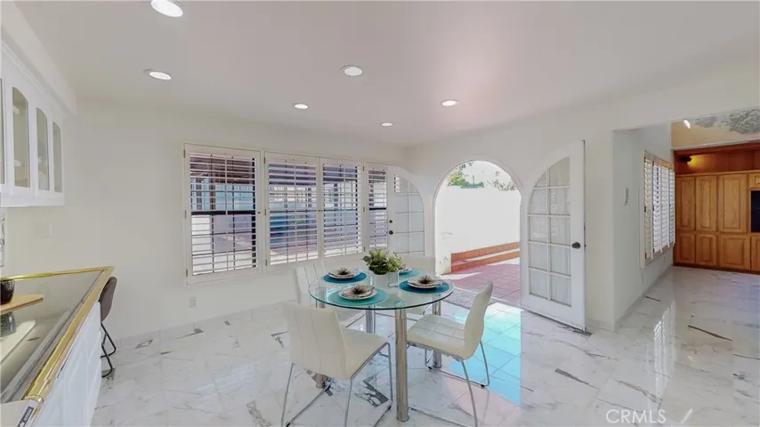 Additionally, a breakfast nook, a menu desk, a view through plantation shutters and rounded French double doors to rear yard