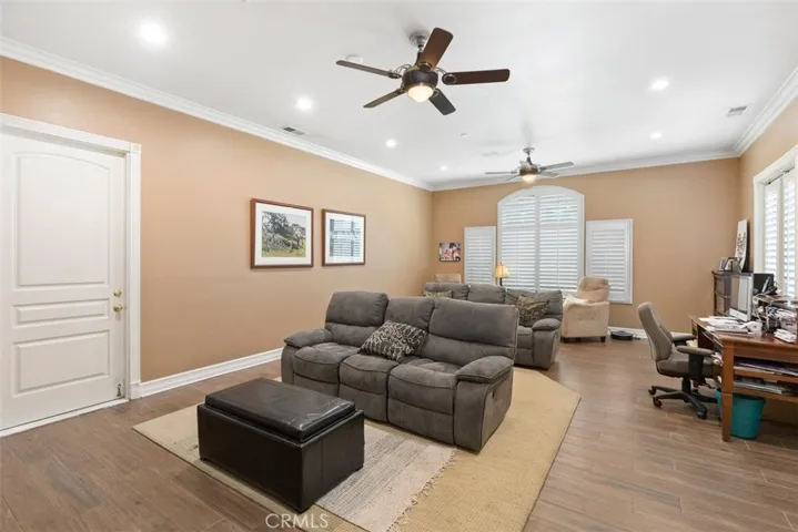 bonus room with two ceiling fans, crown molding and plantation shutters