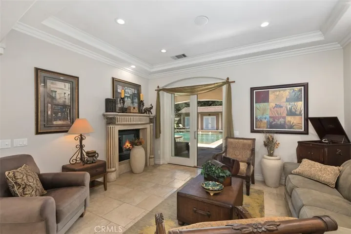 Formal living with coffered ceilings, crown molding, fireplace and direct access to pool area