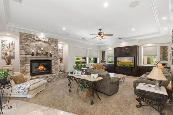 Family room with fireplace, ceiling fan, coffered ceiling, crown molding and custom built-ins