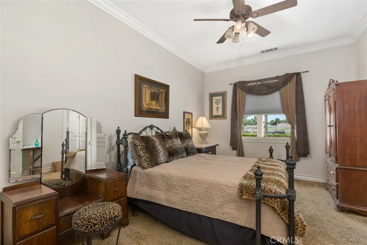 secondary bedroom with ceiling fan and crown molding