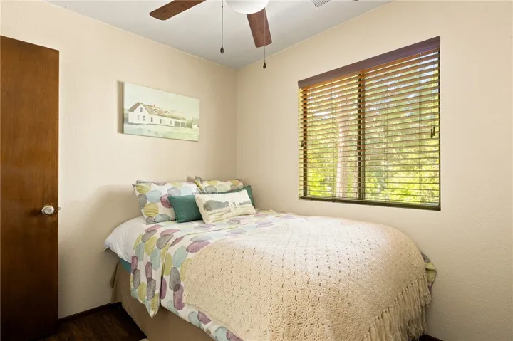 Bedroom with wood blinds and ceiling fan.