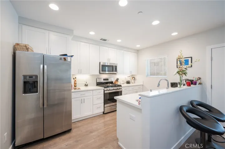 GE STAINLESS STEEL APPLIANCES LARGE SINGLE BLANCO SINK WITH KOLHER FAUCET. WARM STONE SLAB QUARTZ COUNTERTOPS.