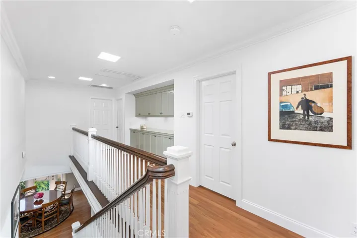 Upstairs features dark oak wood floors and wainscotting going up the stairwell.