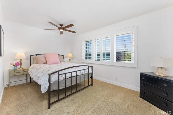 Nicely sized secondary bedroom with a ceiling fan, plantation shutters and plush carpet.