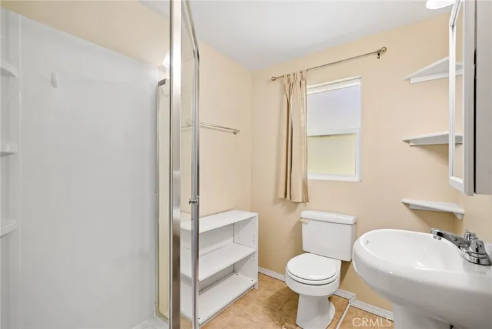 The bathroom has a full shower, pedestal sink and storage.