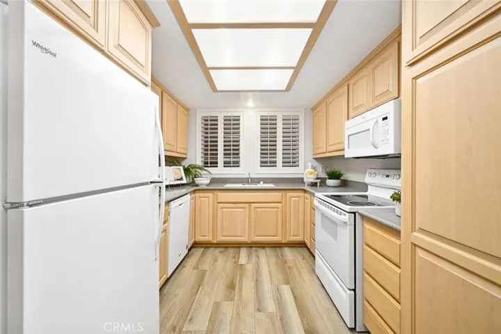 Spacious kitchen with maple cabinets and solid surface counters. Lots of storage. White appliances include oven, dishwasher, refrigerator and micro-wave